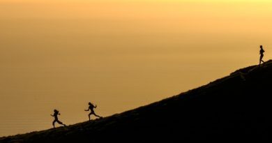 Girls enjoying running meditation down a large hill at sunset.