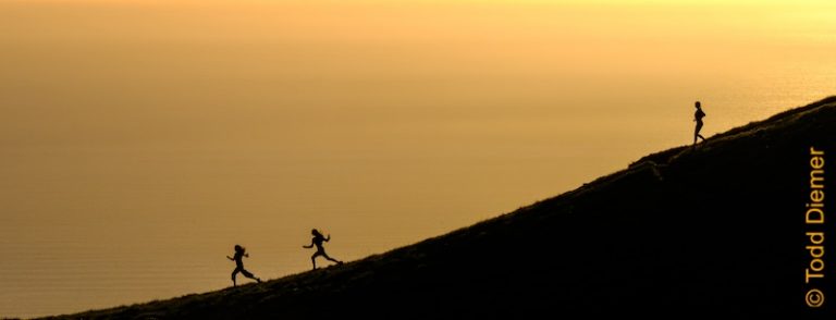 Girls enjoying running meditation down a large hill at sunset.