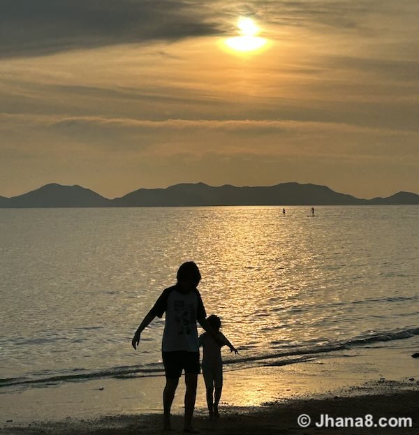 2 children walking on a beach at sunset in Thailand.