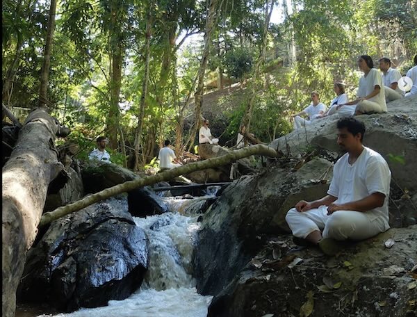 Pa Pae retreat participants meditating alongside a natural freshwater stream.